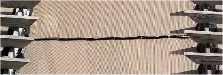cableAfter3 Tan&Black 80% knit shade panel with grommeted pinch pleat in middle supported by cable and rope on wood trellis