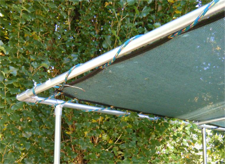 panelLacedRope Green 60% knit shade panel installed with rope laced from perimeter grommets on fencing top rail pipe frame trellis