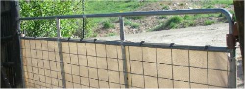 Heavy-duty UV stabilized locking clip fasteners on fabric and then attached to wire mesh fencing on ranch gate