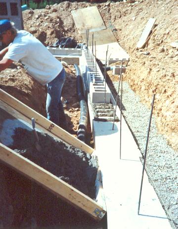 First course of cinder block is laid upon a bed of mortar on the concrete footers.