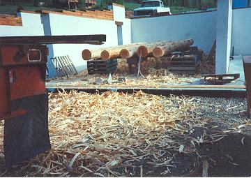 Shipping pallets make perfect benches for hand-stripping logs inside the foundation walls