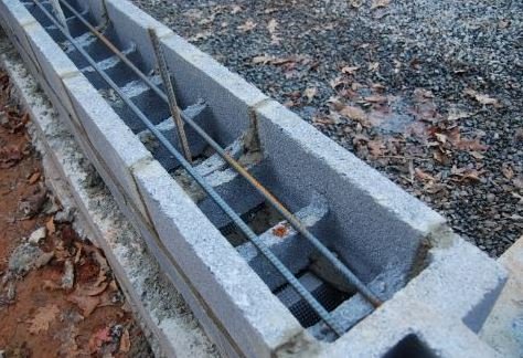 Horizontal bond beam knock-out blocks installed in a concrete cinder block wall with rebar reinforcement